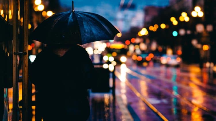 silhouette of person holding umbrella with colorful lights at night