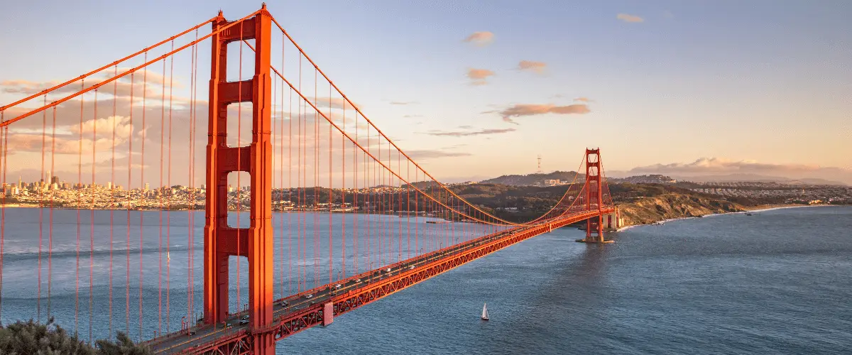 Tour group posing at a scenic viewpoint overlooking the Golden Gate Bridge and San Francisco Bay on a clear day.