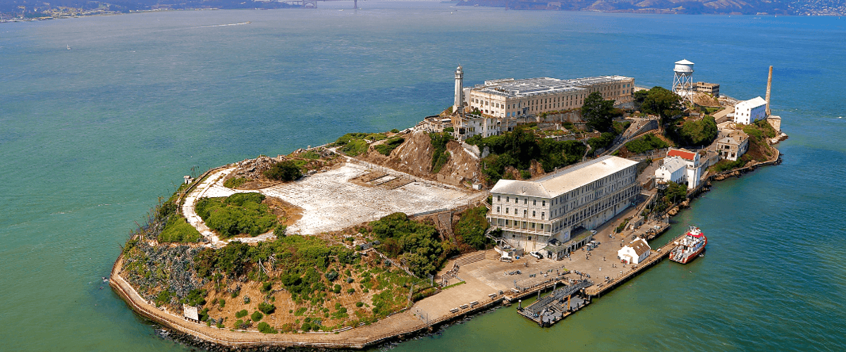 Scenic aerial shot of Alcatraz Island surrounded by the waters of San Francisco Bay, with the city skyline in the background
