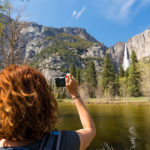 red-headed woman taking a photo in yosemite