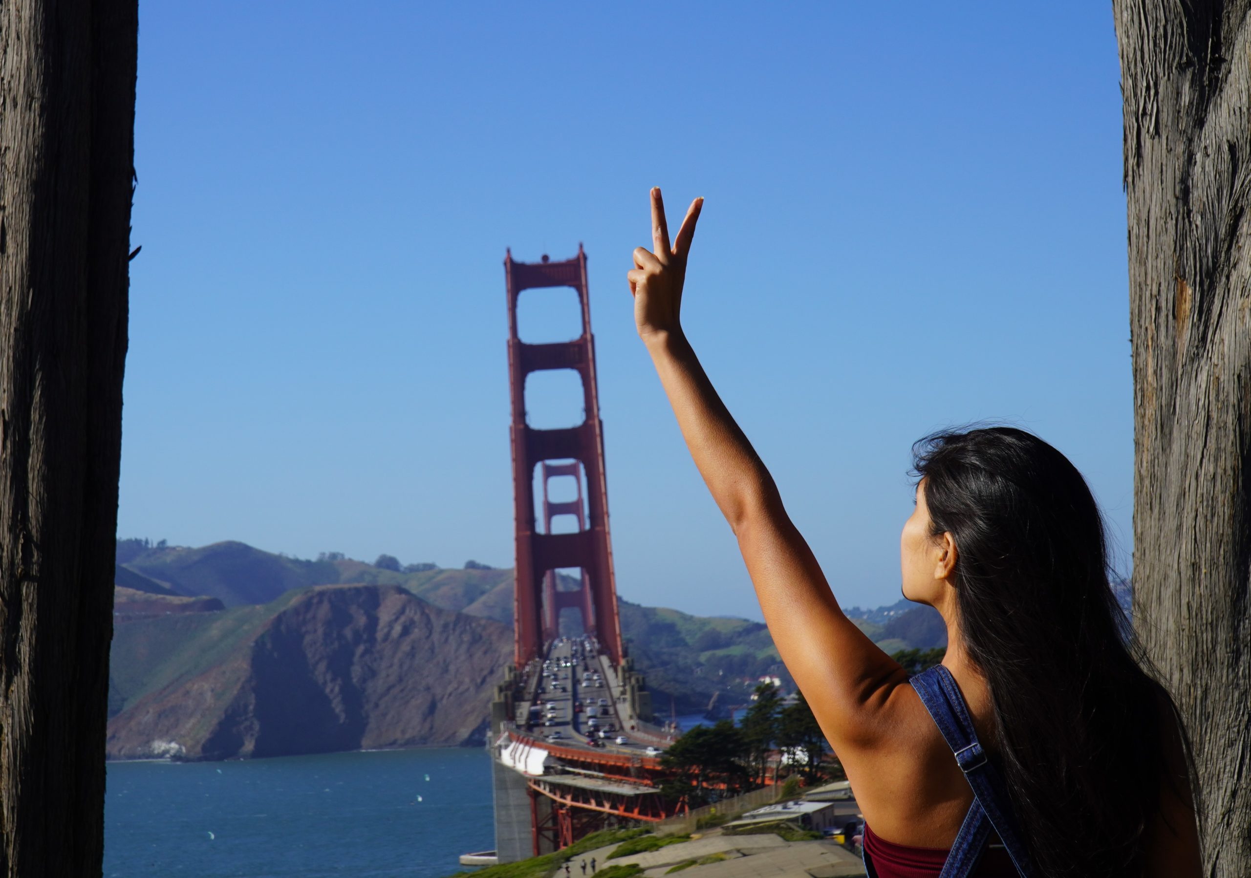 person holding up a peace sign with the golden gate in the background