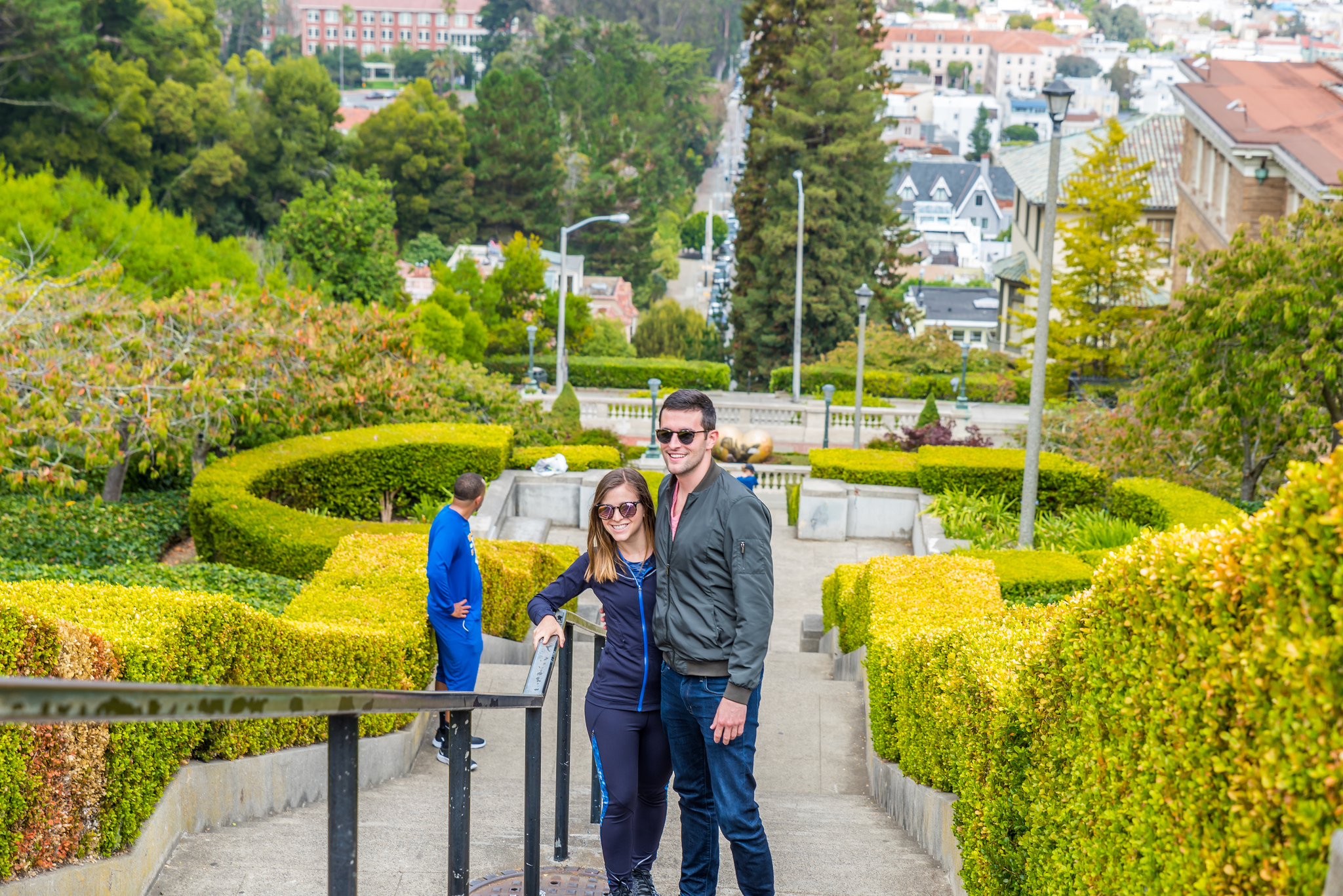 couple posing on stairs between green shrubs