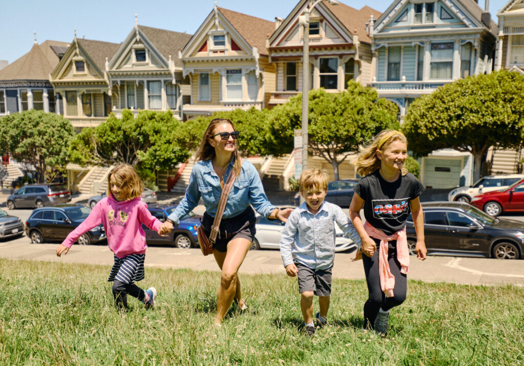 Woman and children walking hand-in-hand in front of the famous Painted Ladies homes in Alamo Square