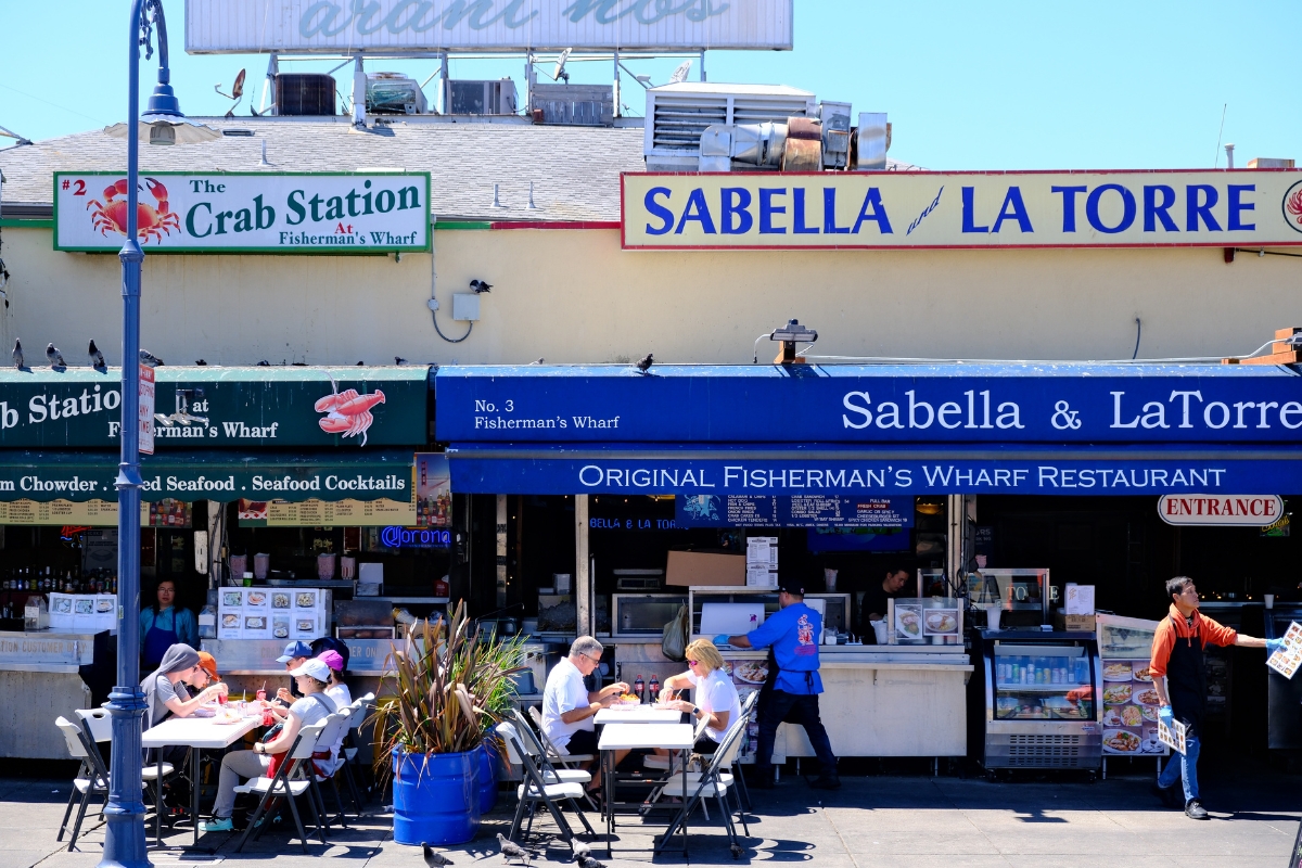 Outdoor dining area with seafood restaurants including Sabella & La Torre and The Crab Station at Fisherman's Wharf.
