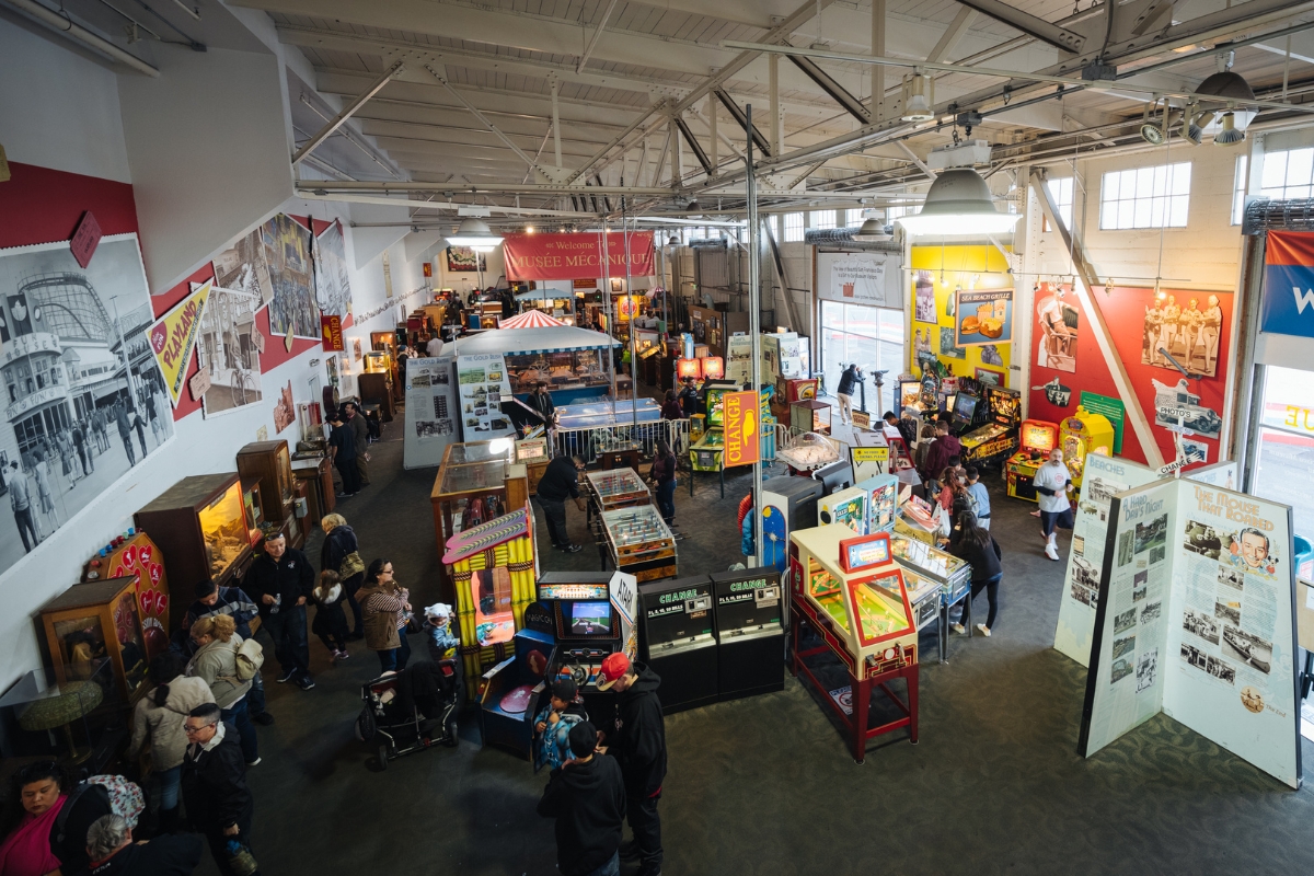 Indoor mechanical museum featuring vintage arcade games, pinball machines, and historical exhibits with visitors exploring the collection