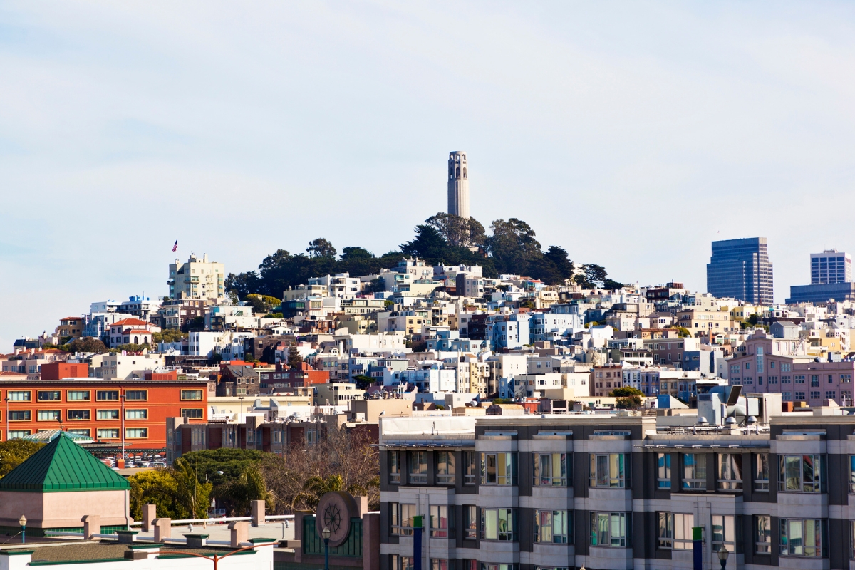 San Francisco cityscape view of Telegraph Hill with Coit Tower, surrounding hillside residential buildings, and downtown architecture