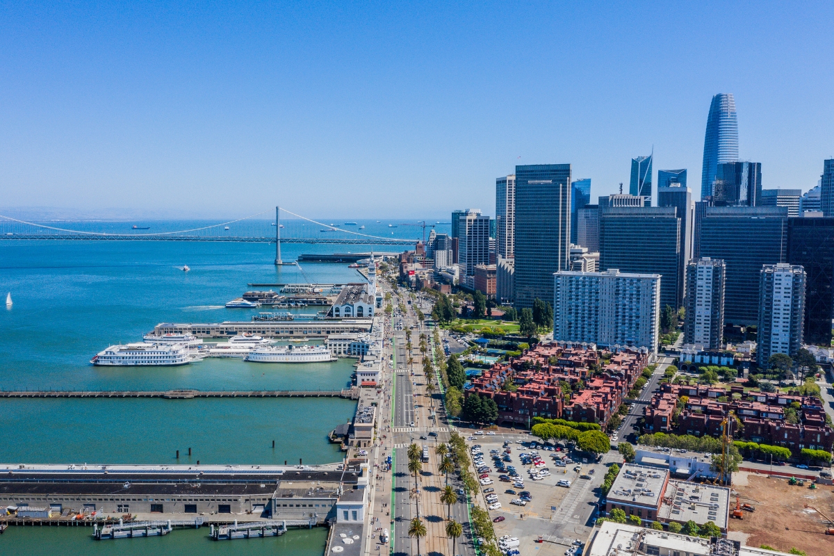 Aerial view of San Francisco's Embarcadero waterfront, Bay Bridge, ferry terminals, and downtown skyscrapers on clear day
