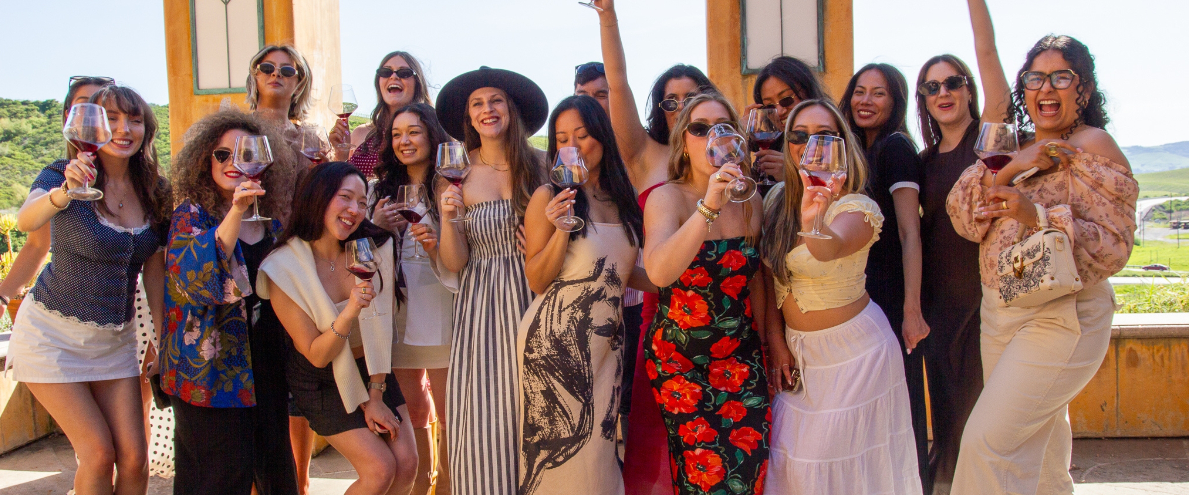 Group of women celebrating with wine glasses at a scenic vineyard terrace with mountain views in California wine country