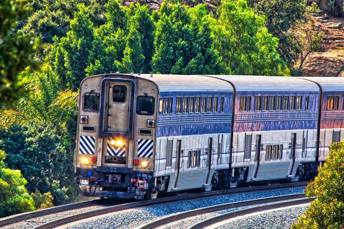 Silver and blue Caltrain passenger train traveling through lush green California hillside