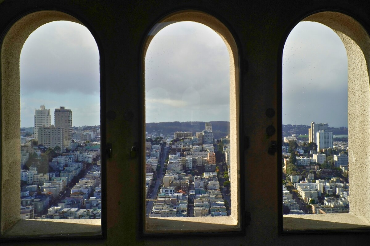 San Francisco cityscape viewed through three arched windows of Coit Tower observation deck