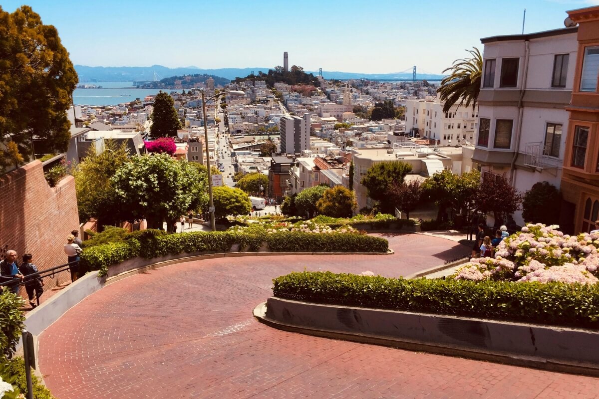 View from Lombard Street showing Coit Tower, San Francisco cityscape, and Bay Bridge in distance