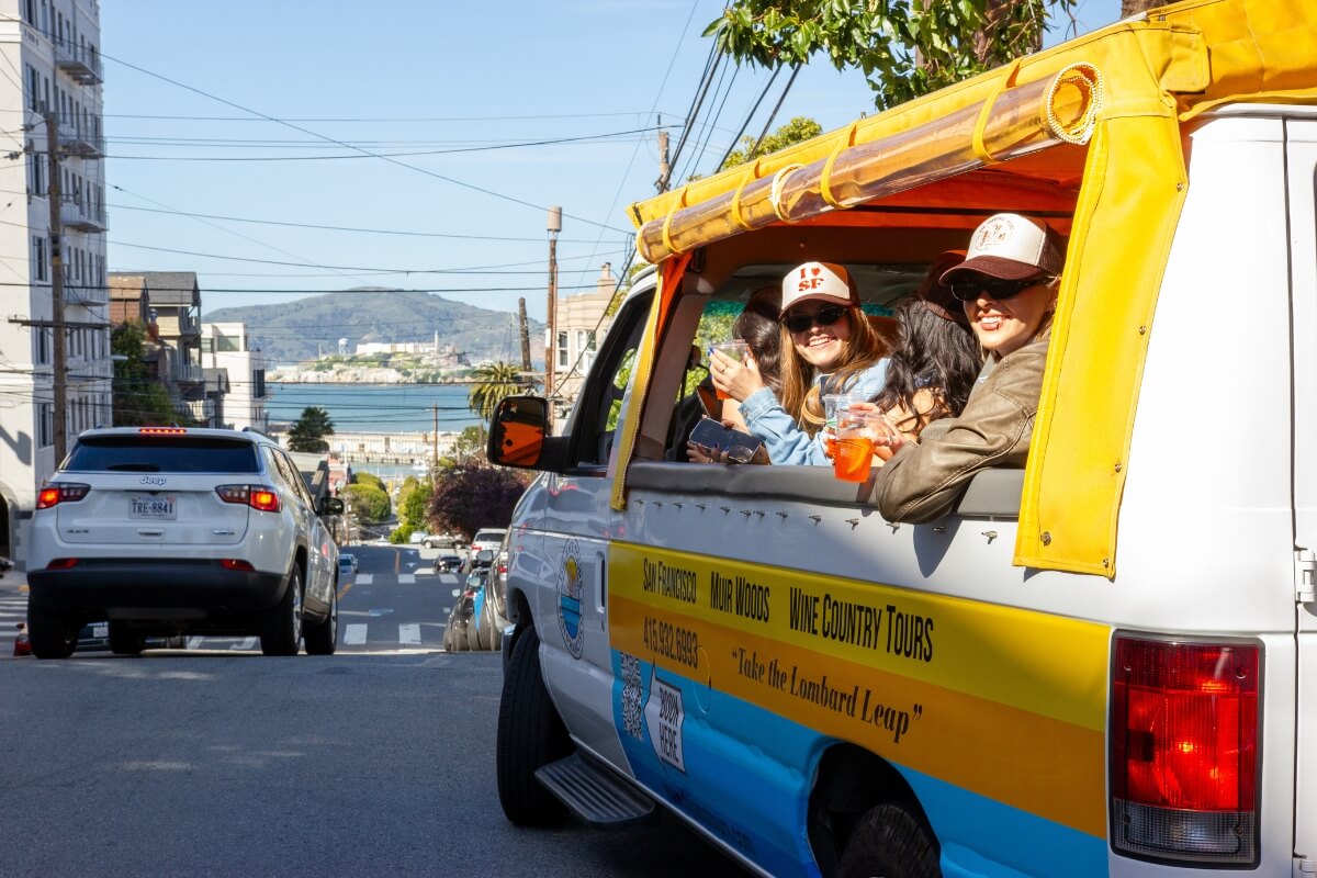 Yellow Wine Country Tours van with smiling passengers enjoying San Francisco neighborhood views
