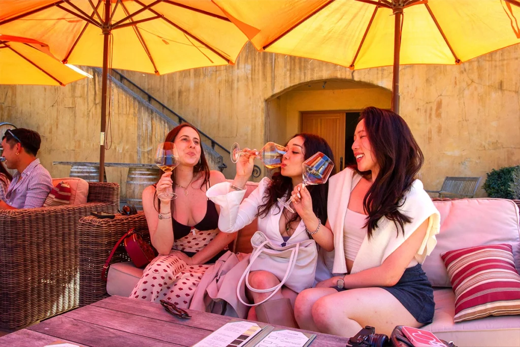 Woman smiling while tasting wine during a vineyard tour, capturing the joy of a wine tasting experience.