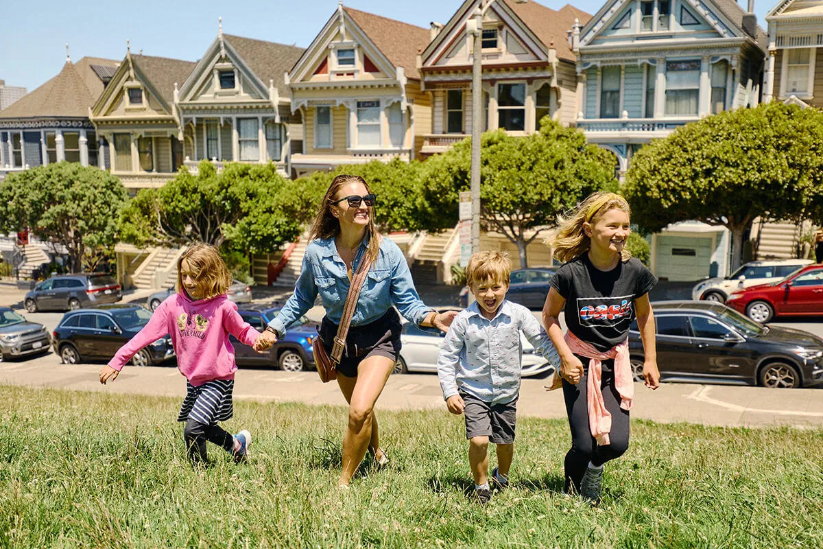 Family sitting on the grass enjoying the Painted Ladies Victorian houses in San Francisco.