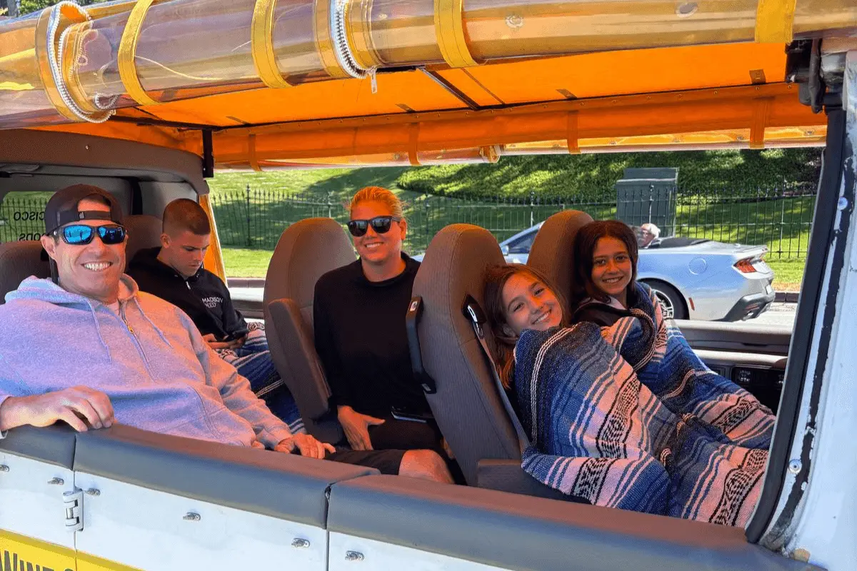 Family enjoying a sunny San Francisco day on a private tour with Dylan’s Tours, bundled up under blankets in an open-air vehicle.