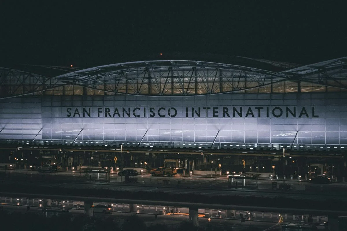 Exterior view of San Francisco International Airport (SFO) illuminated at night, showing the terminal entrance and signage.