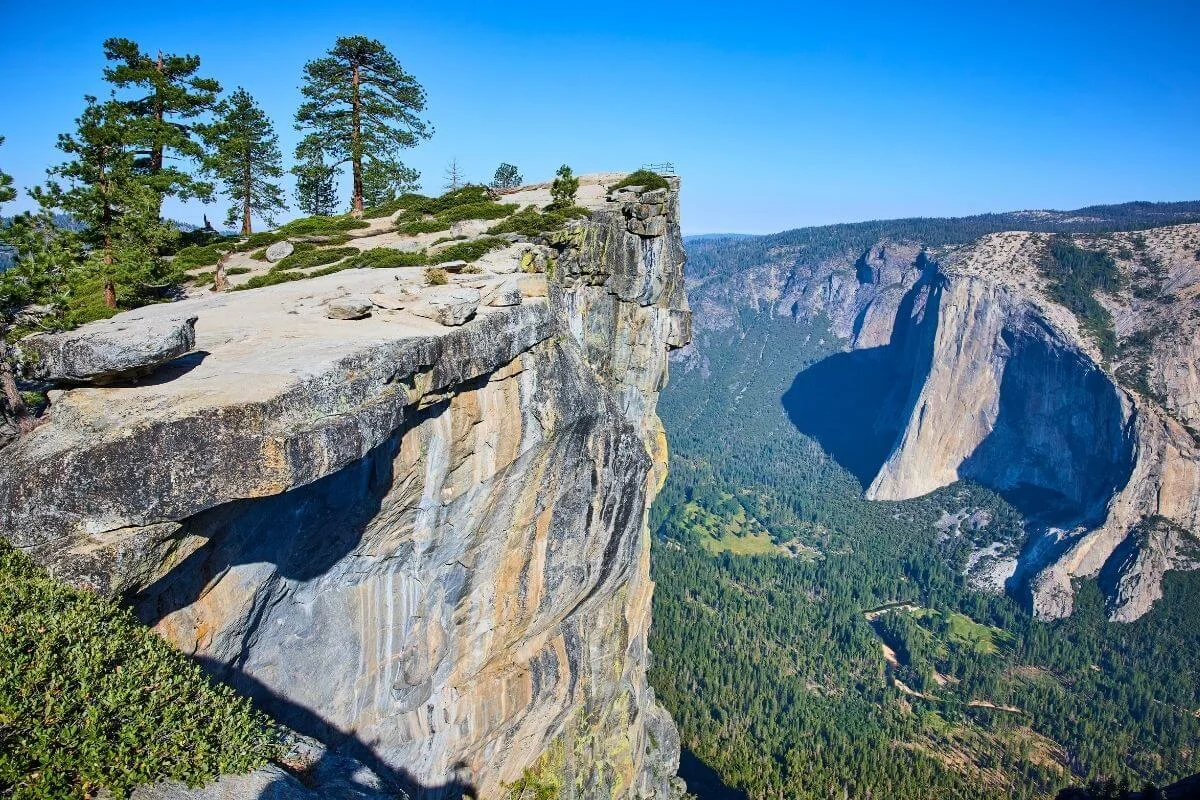 High cliff overlooking Yosemite Valley with granite rock faces and forested landscape in Yosemite National Park
