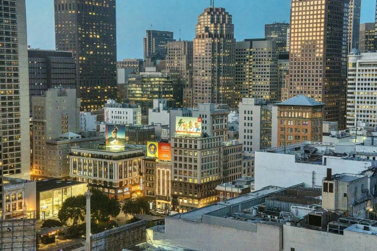 Downtown San Francisco skyline at dusk with illuminated buildings and city streets viewed from above