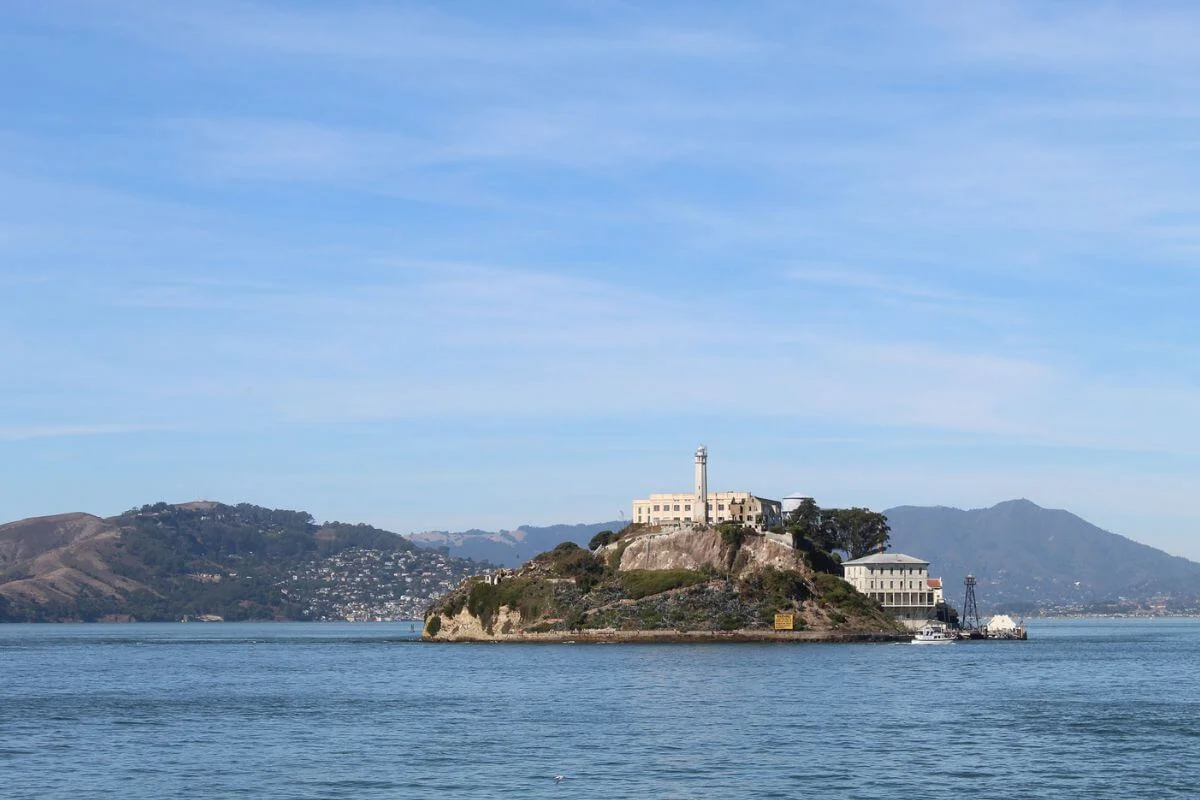 Alcatraz Island prison building seen across San Francisco Bay with surrounding hills in the background