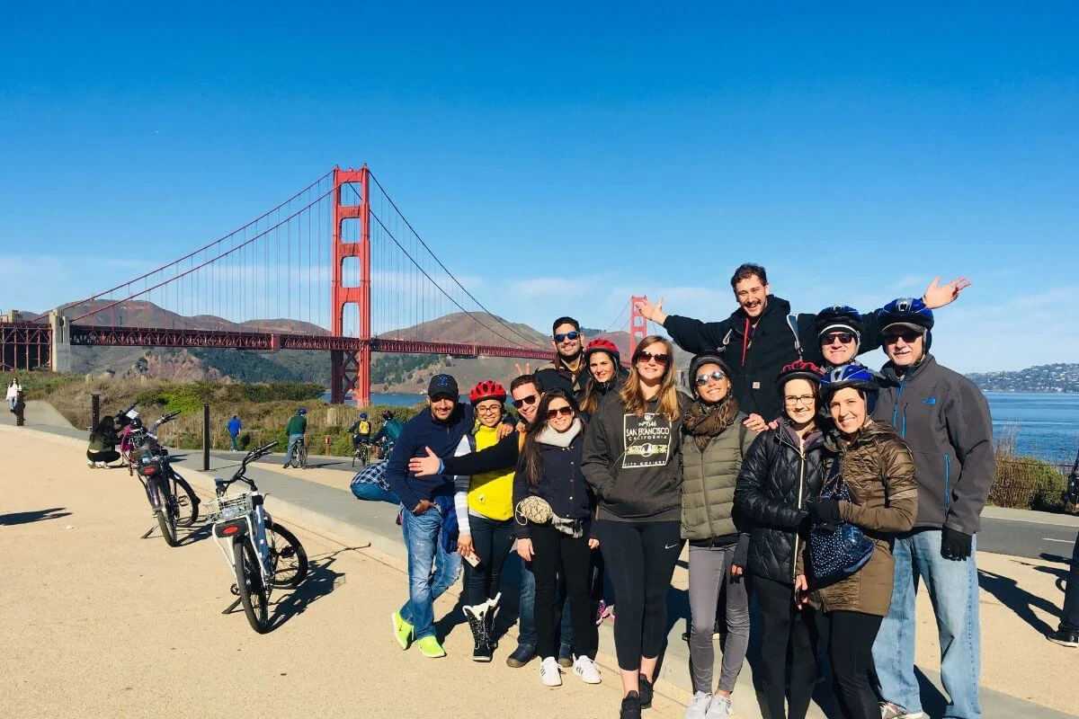 Group of tourists posing with bikes near the Golden Gate Bridge in San Francisco on a sunny day