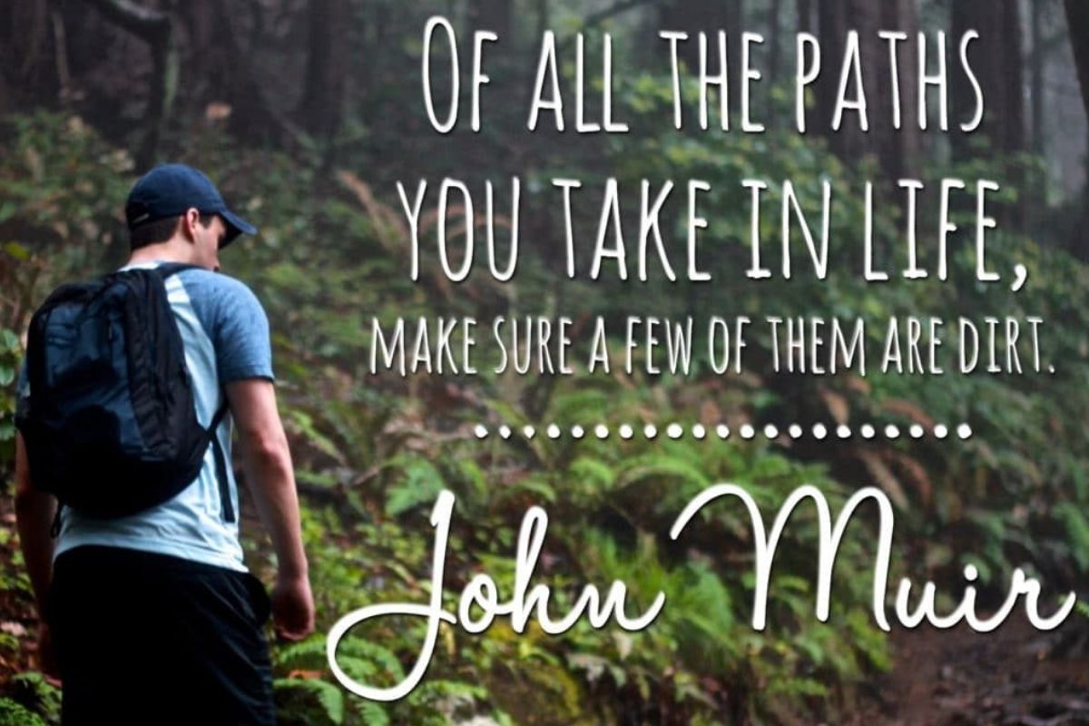 Hiker with a backpack walking along a forest trail with a John Muir quote about life and nature overlaid on the image.