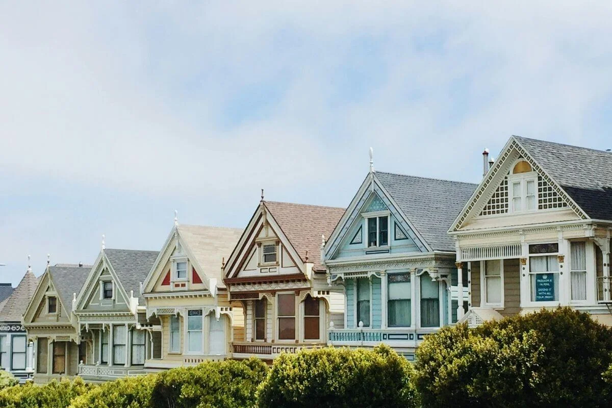 Iconic Painted Ladies row of colorful Victorian houses in San Francisco with manicured greenery in the foreground.
