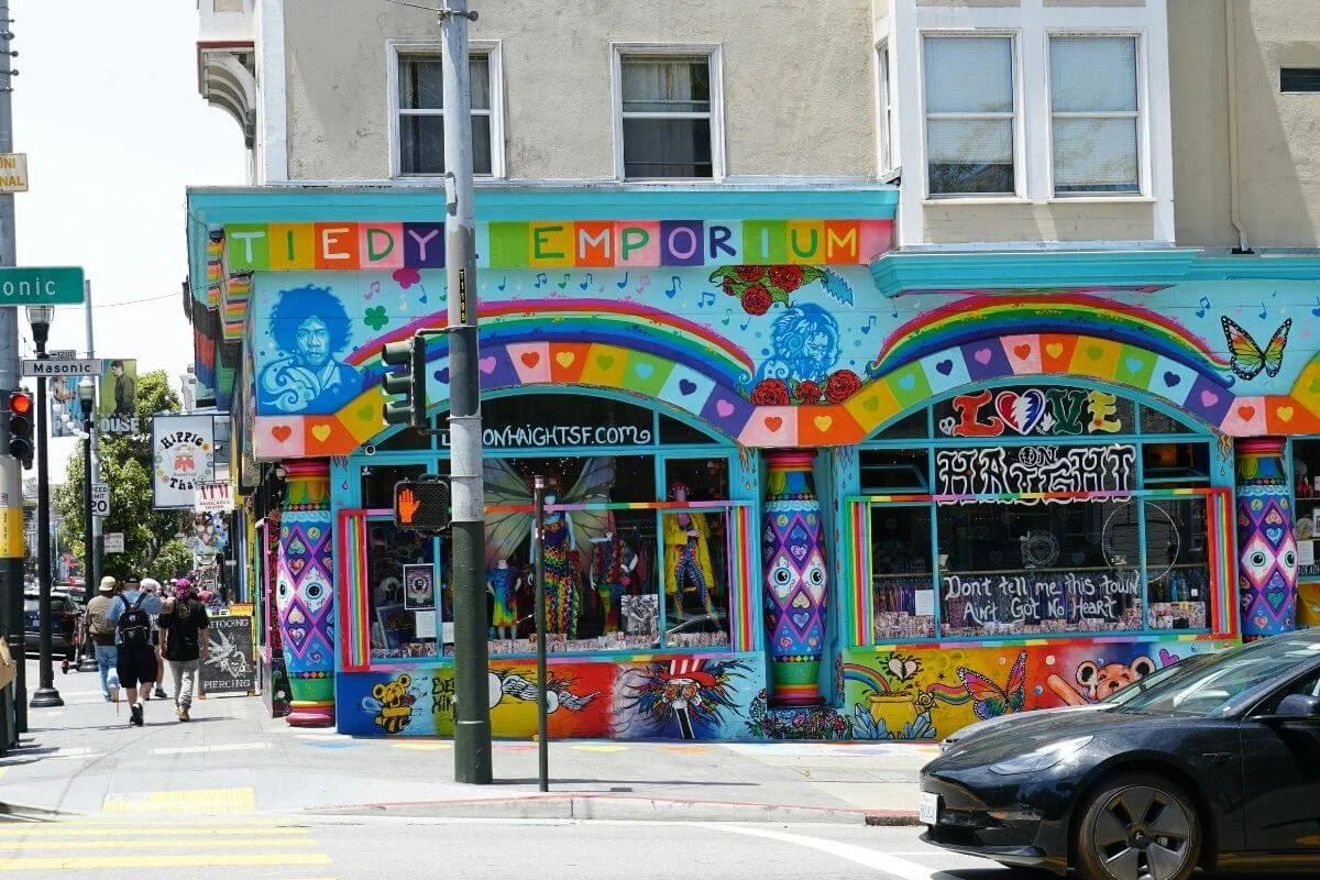 Vibrant and artistic storefront in Haight-Ashbury, San Francisco, featuring colorful murals, rainbow designs, and pedestrians walking by.