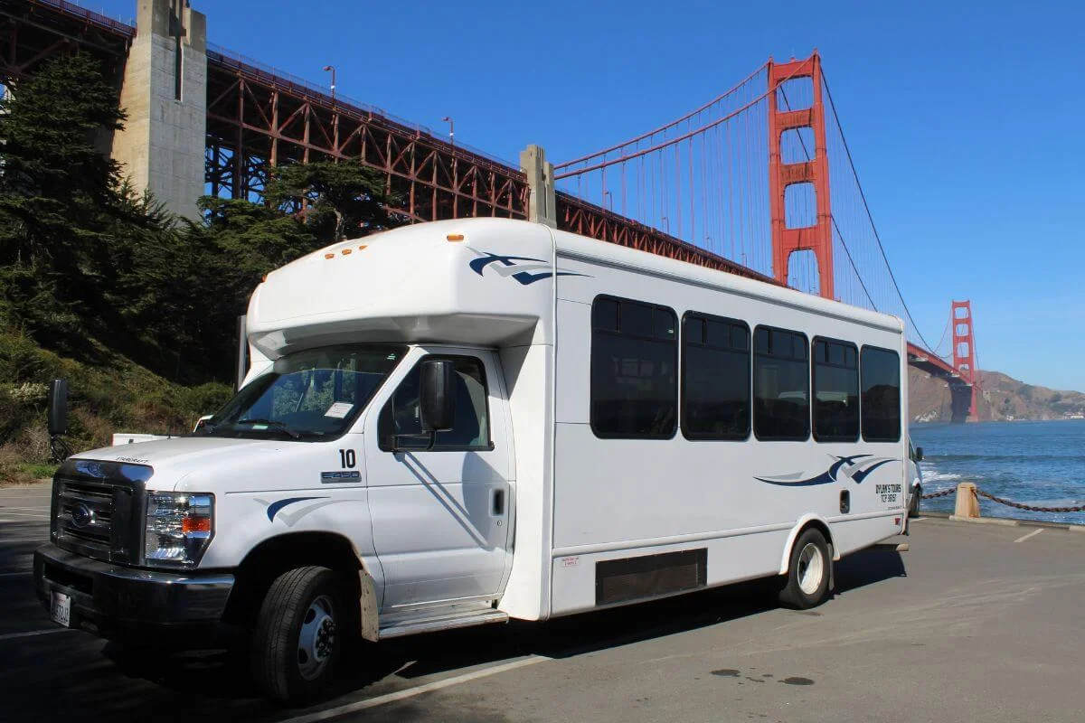 Dylan's Tours minibus parked near Fort Point beneath the Golden Gate Bridge's southern tower