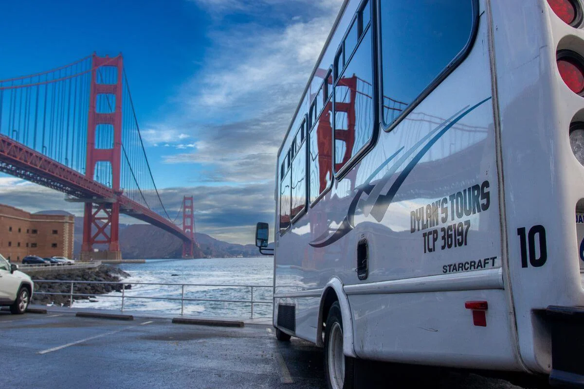 Dylan's Tours minibus with Golden Gate Bridge reflected on its windows parked at waterfront lot