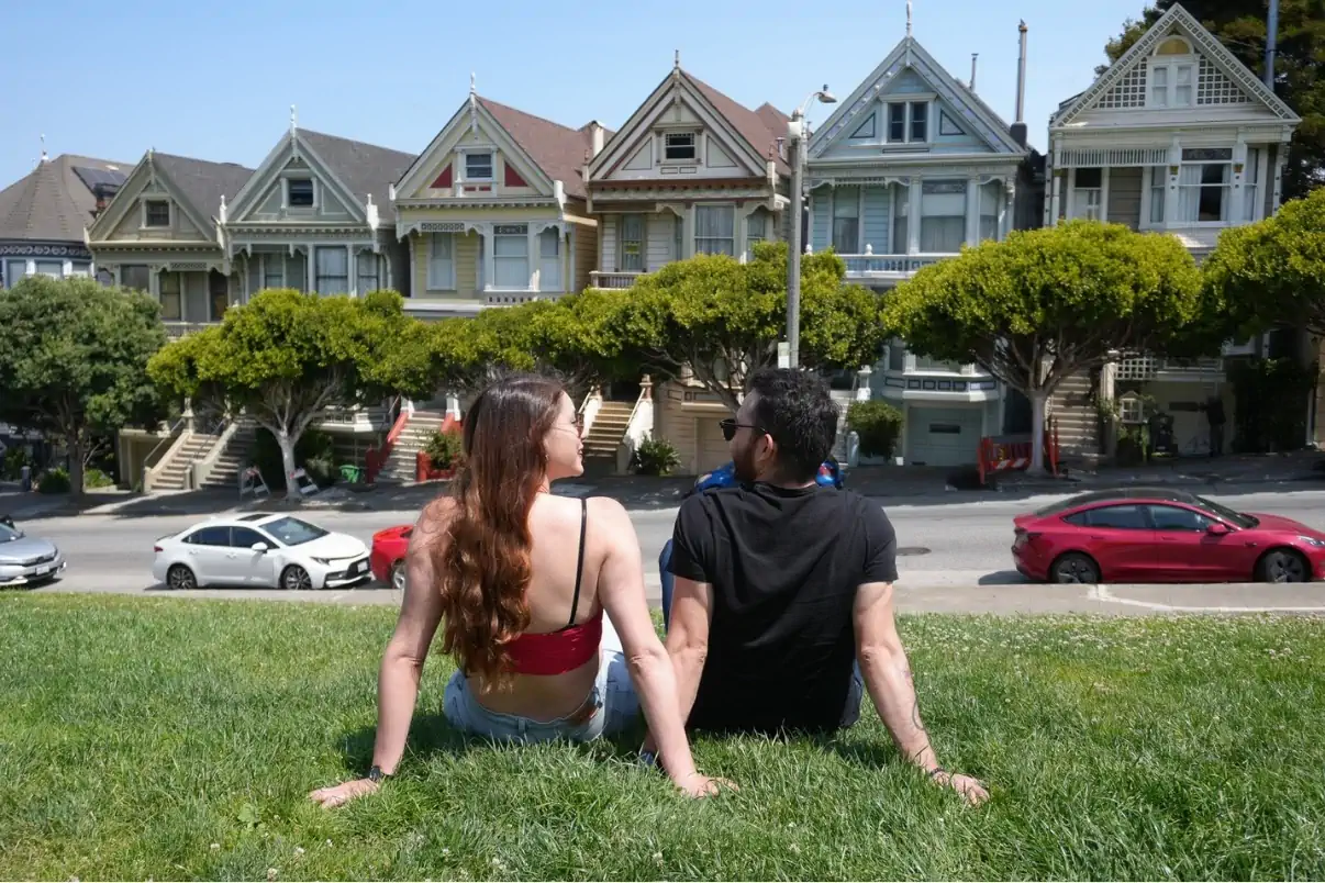 Visitors relaxing in front of the Painted Ladies at Alamo Square