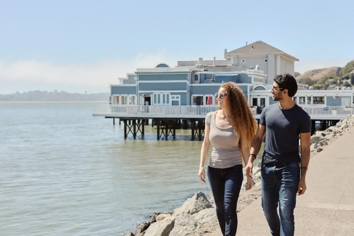 Couple walking along the San Francisco waterfront near the bay