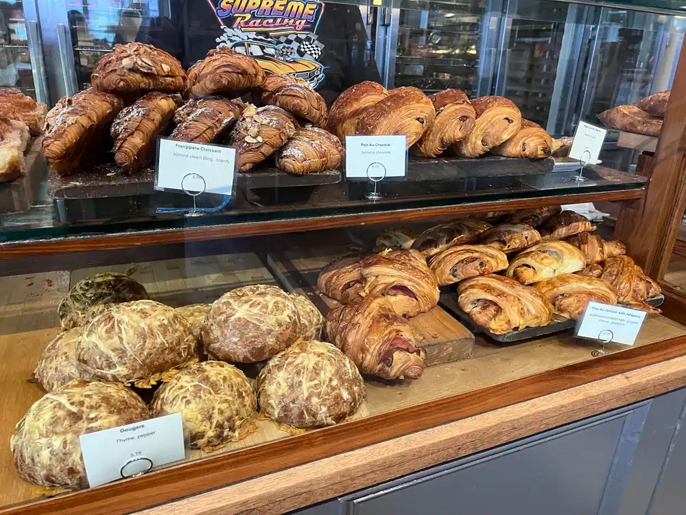 Bakery case filled with almond croissants, pain au chocolat, ham and jalapeño pastries, and cheese gougères at Tartine
